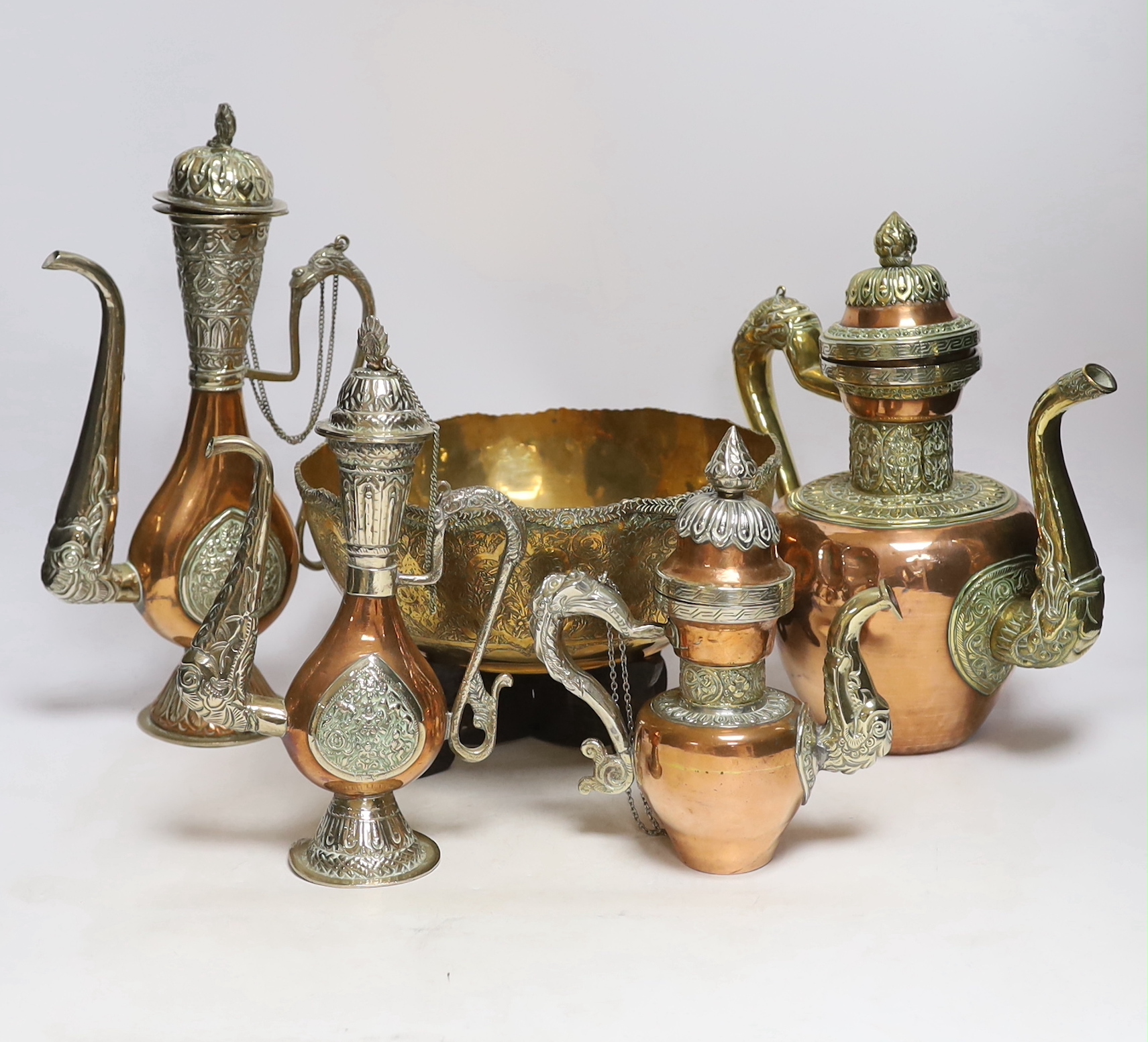 Four Tibetan overlaid copper teapots and an engraved brass bowl, tallest 34cm